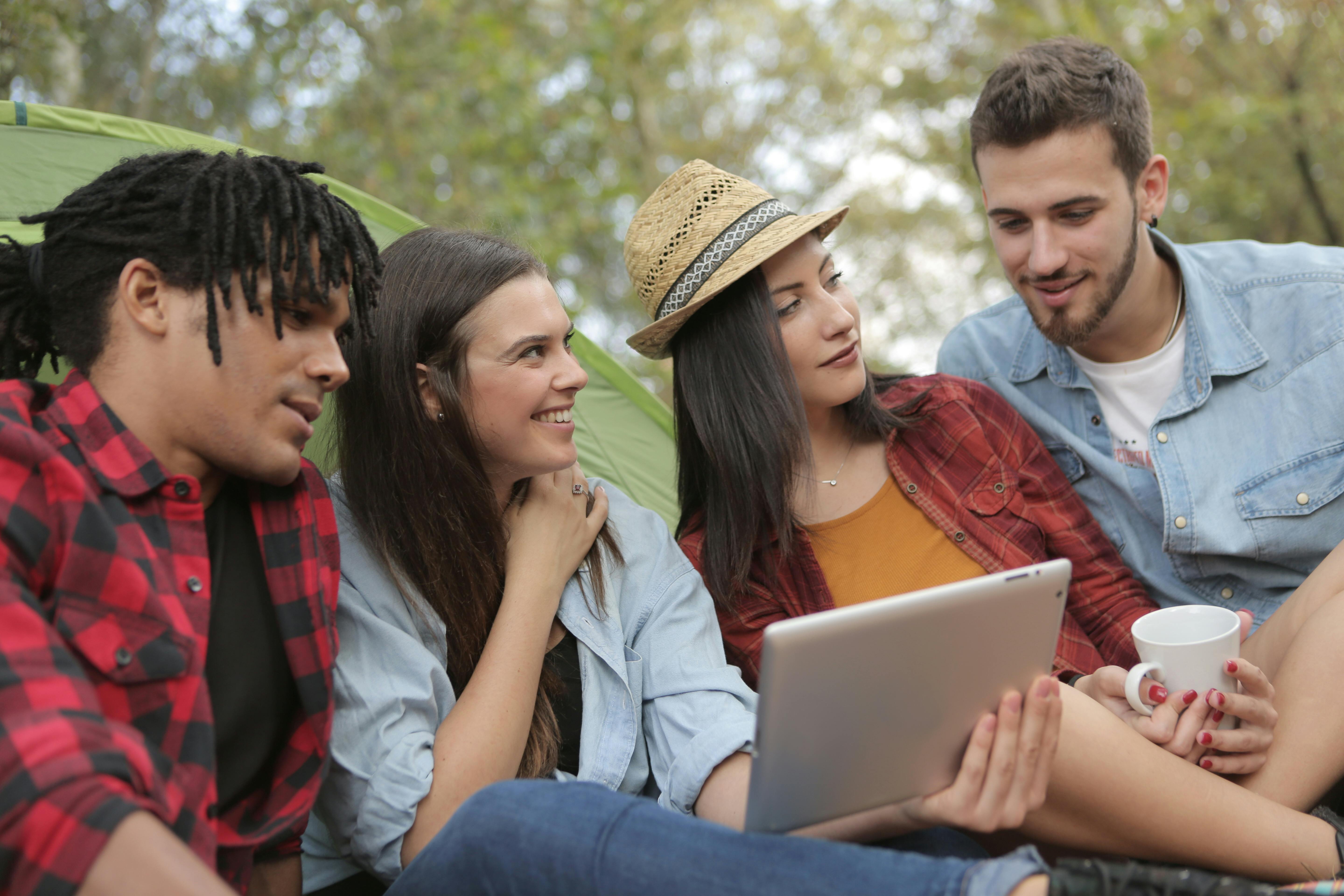 happy multiethnic people surfing tablet on nature