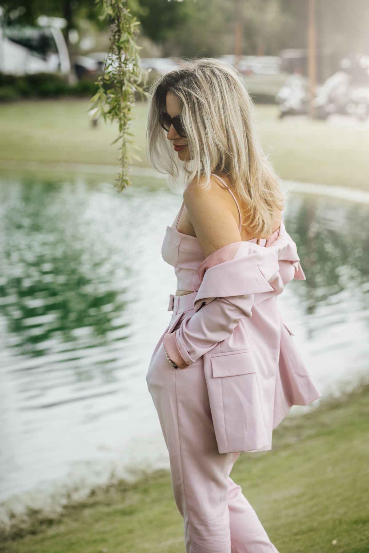 Woman in a pastel pink suit by a lake
