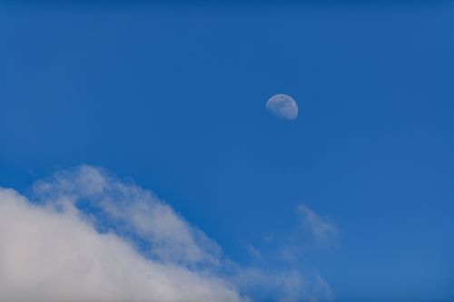 Free A crescent moon visible during the day against a blue sky scattered with clouds. Stock Photo