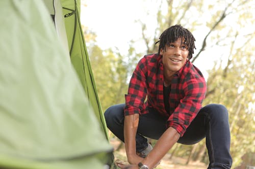 Free Ethnic man pitching tent in park Stock Photo