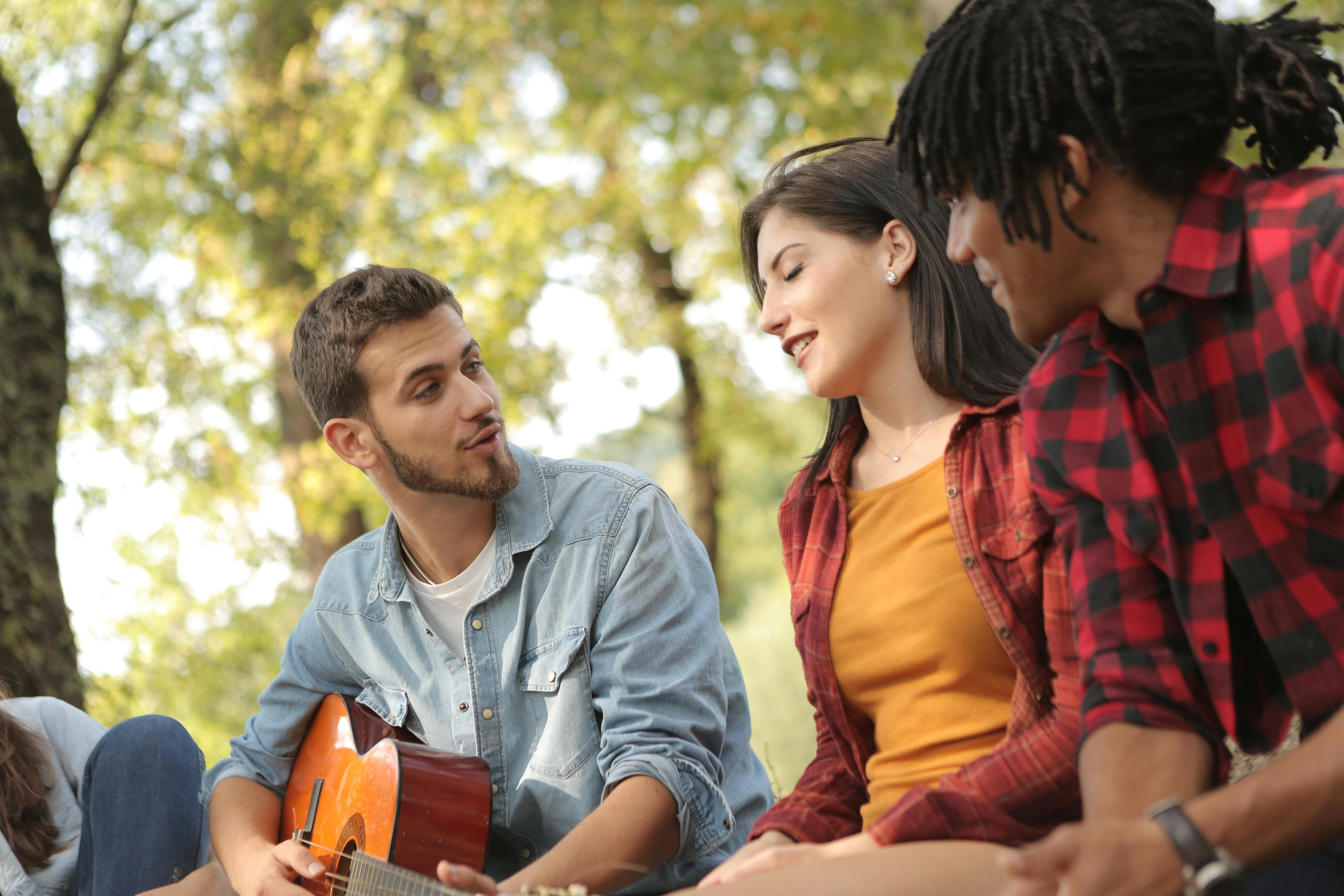 male with guitar singing with friends