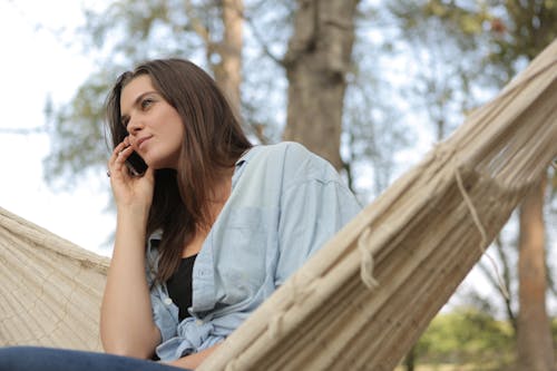 Woman Sitting on Hammock While Using Smartphone