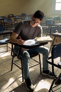 Focused student in a classroom taking notes during daylight.