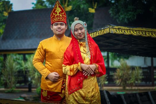Portrait of a couple in traditional Indonesian attire with intricate details, captured outdoors.
