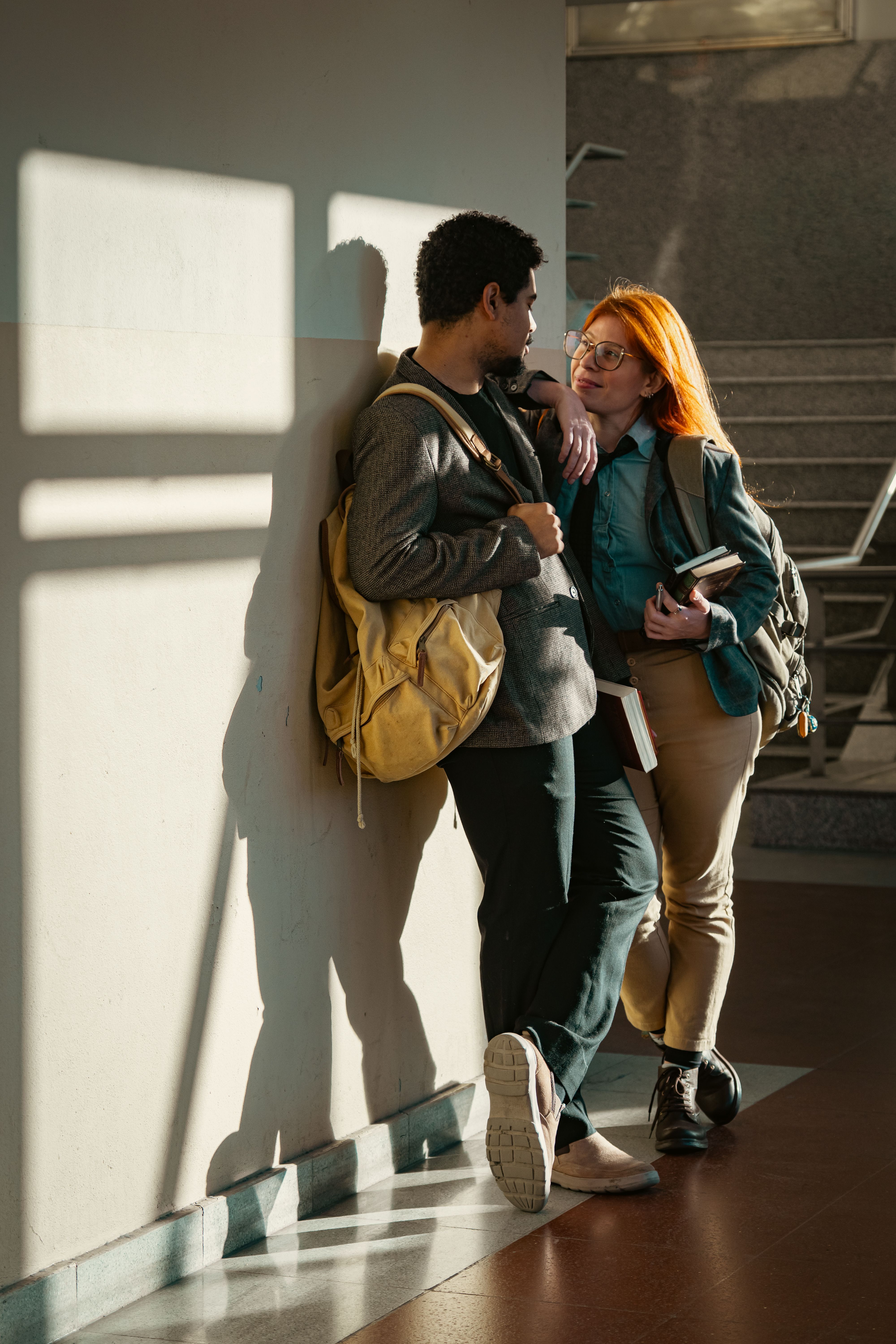 A young couple of students conversing in a sunlit hallway, Buenos Aires.