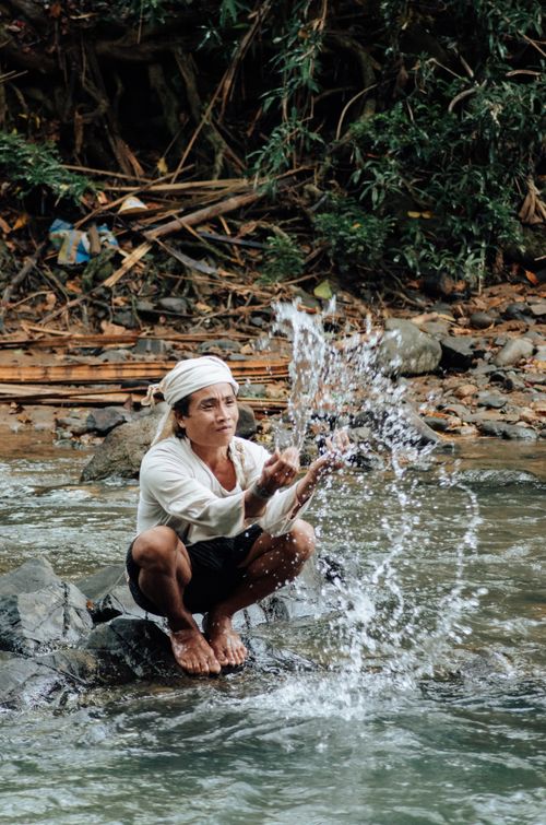 Free A man joyfully splashes water in a river in Banten, Indonesia, amidst lush greenery. Stock Photo