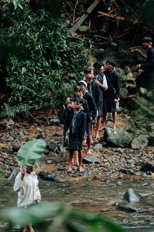Free Traditional South Asian group by a river in Banten, Indonesia, holding large leaves. Stock Photo