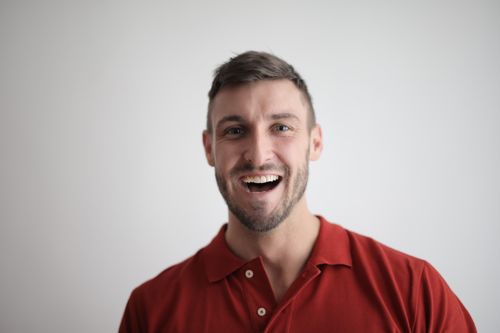 Free A cheerful man smiling broadly in a red polo shirt against a white background. Stock Photo