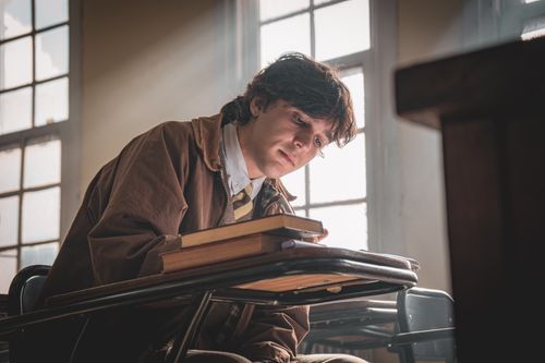 Free A student deep in thought at a classroom desk, sunlight streaming through the window. Stock Photo