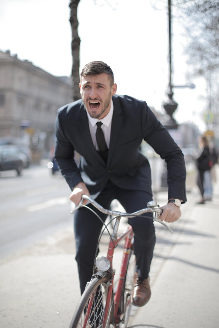 Man In Black Suit Jacket Riding Red Bicycle On Road