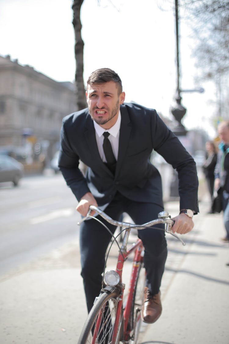 Man In Black Suit Jacket Riding Red Bicycle On Road