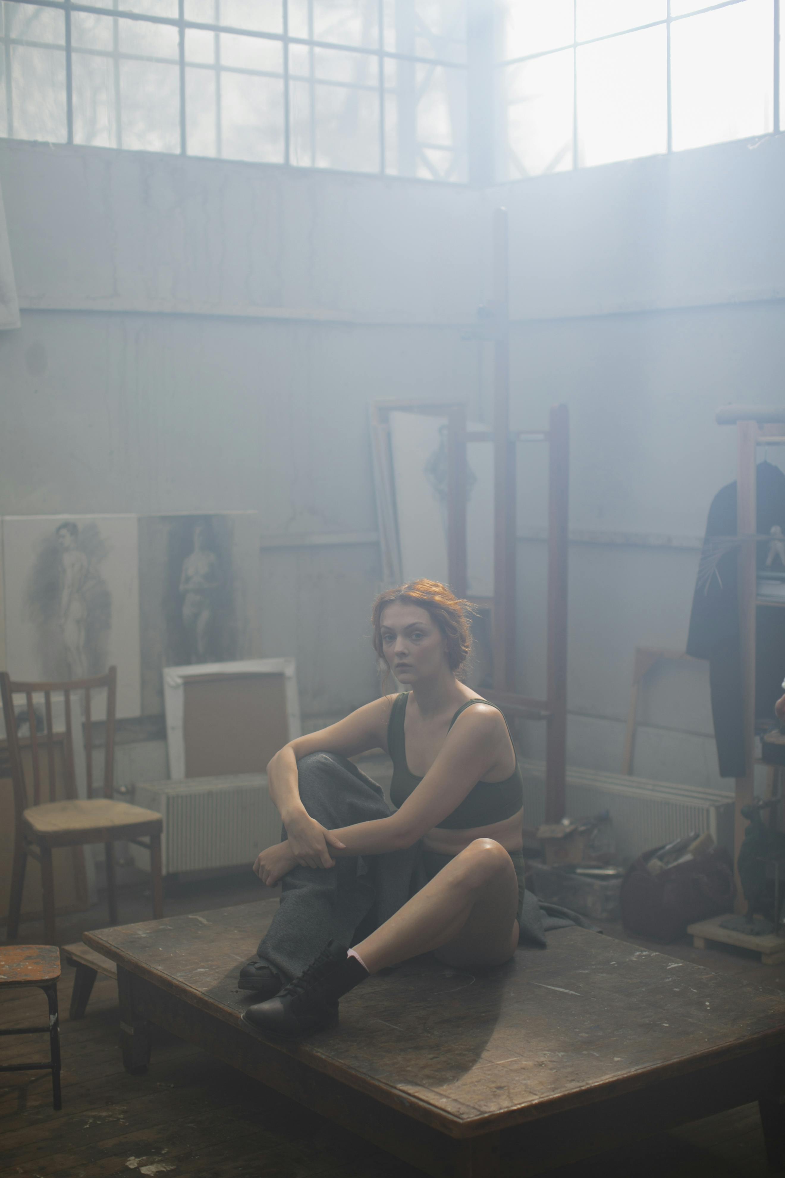 一位女性坐在雾蒙蒙、灯光柔和的艺术工作室里，创作肖像