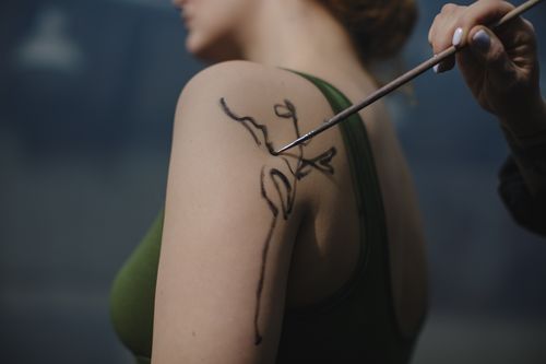 Free Close-up of an artist painting a plant design on a woman's shoulder, showcasing creativity and skill. Stock Photo