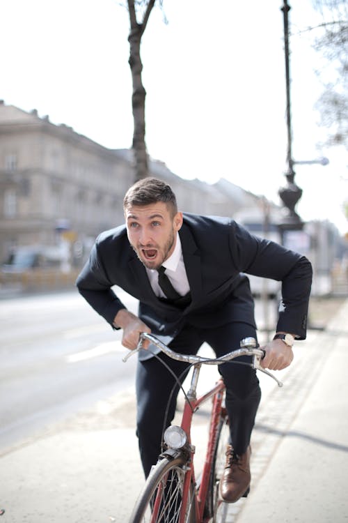Man in Black Suit Jacket Riding Red Bicycle