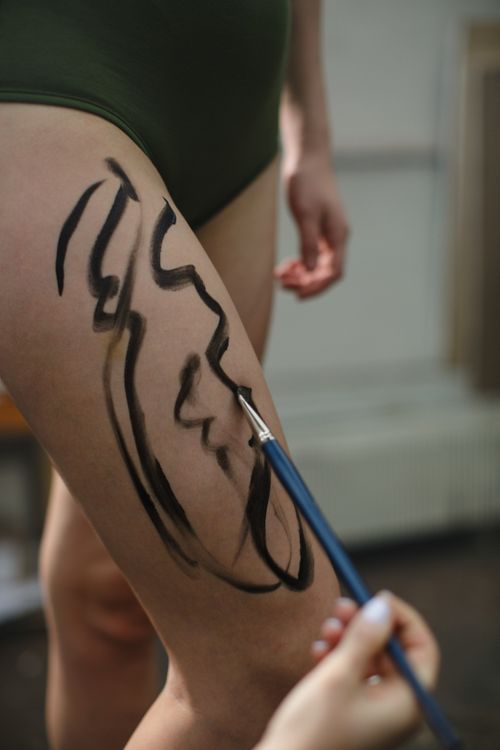 Free A woman's leg being painted with artistic brushstrokes indoors, showcasing body art creativity. Stock Photo