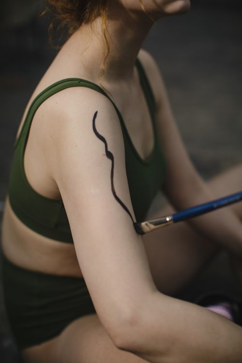 Free Close-up of body painting with brush on woman's arm in creative indoor setting. Stock Photo