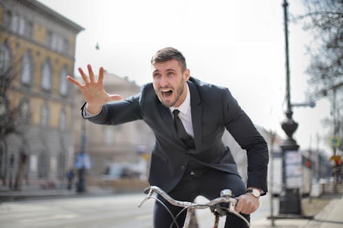 Man in Black Suit Riding on Bicycle