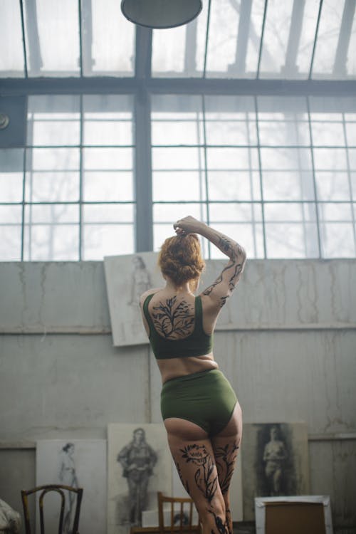 Женщина в черном спортивном бюстгальтере и зеленых шортах с краской для тела