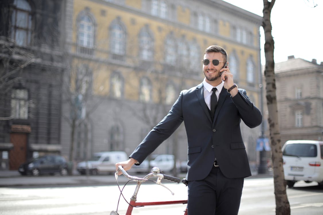 赤い自転車を保持している黒いスーツのジャケットと黒いドレスパンツの男