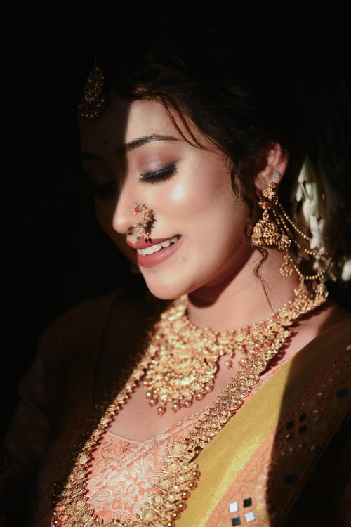 Free A beautiful Indian bride wearing traditional gold jewelry, captured in soft light. Stock Photo