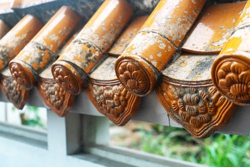 Free Detailed view of weathered orange clay roof tiles with floral decorations, showcasing traditional craftsmanship. Stock Photo
