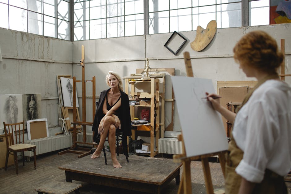 An artist captures a nude model in a natural light-filled studio setting, emphasizing creativity and artistry.