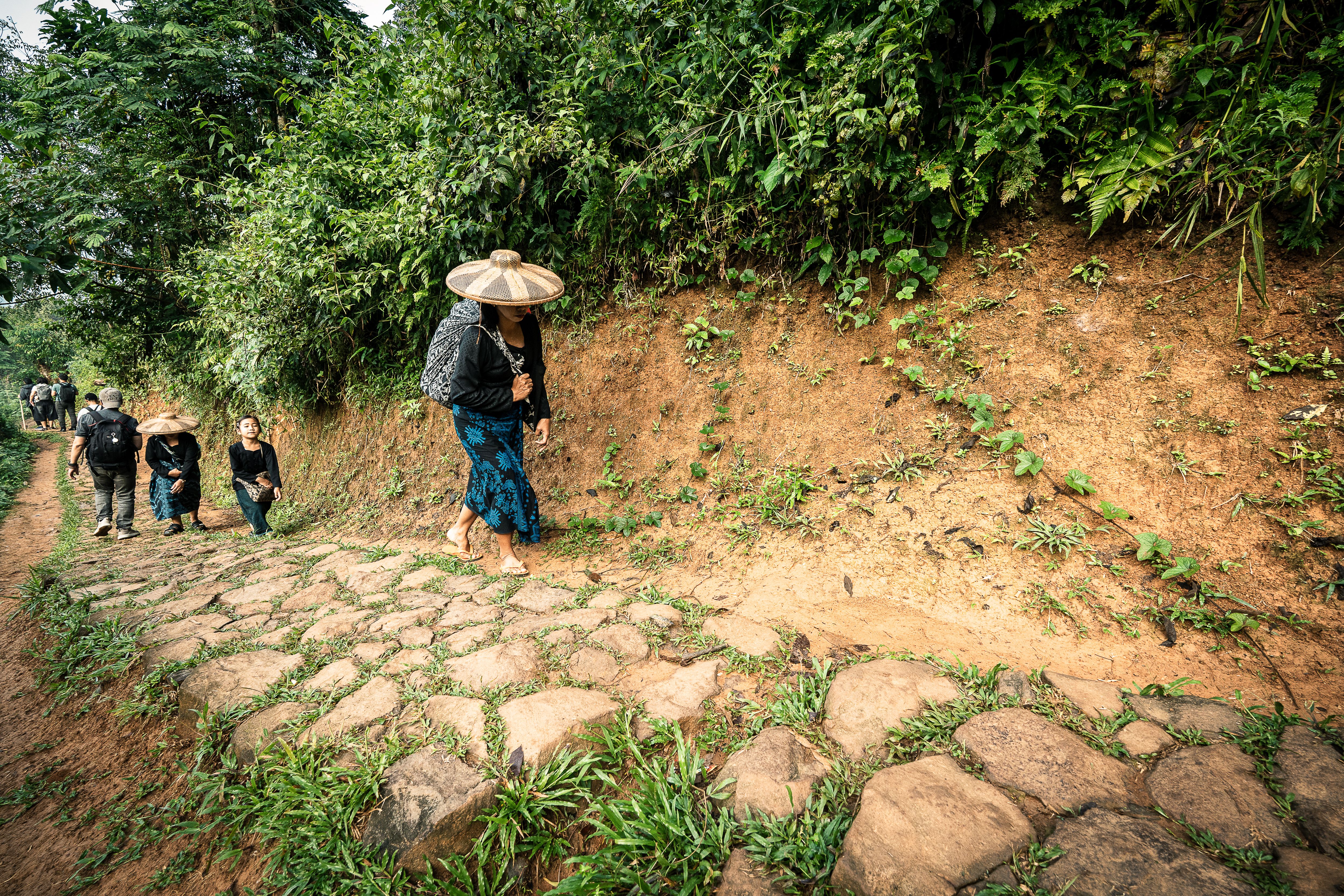 Travelers walking uphill on a traditional path in lush Banten, Indonesia.