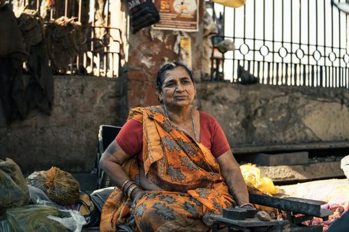 Free A female street vendor sits amidst vibrant fabrics and bags in Ludhiana, Punjab, India. Stock Photo