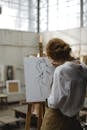 Woman In White Long Sleeves Sketching A Woman