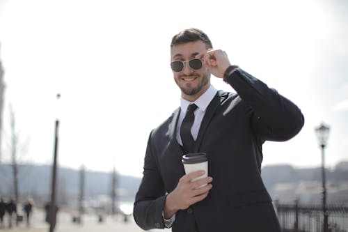 Free Man In Black Suit Holding A White Cup Stock Photo