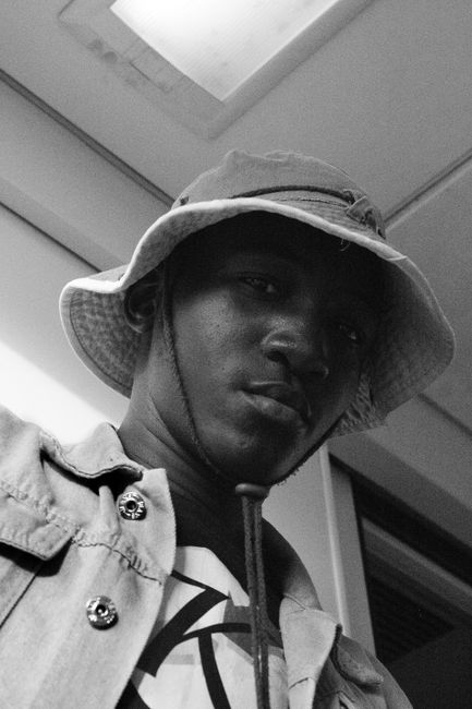 Black and white African American from below wearing bucket hat and shirt looking at camera