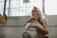 在阳光明媚的工作室里，一位资深女性若有所思而安详地拥抱着雕塑