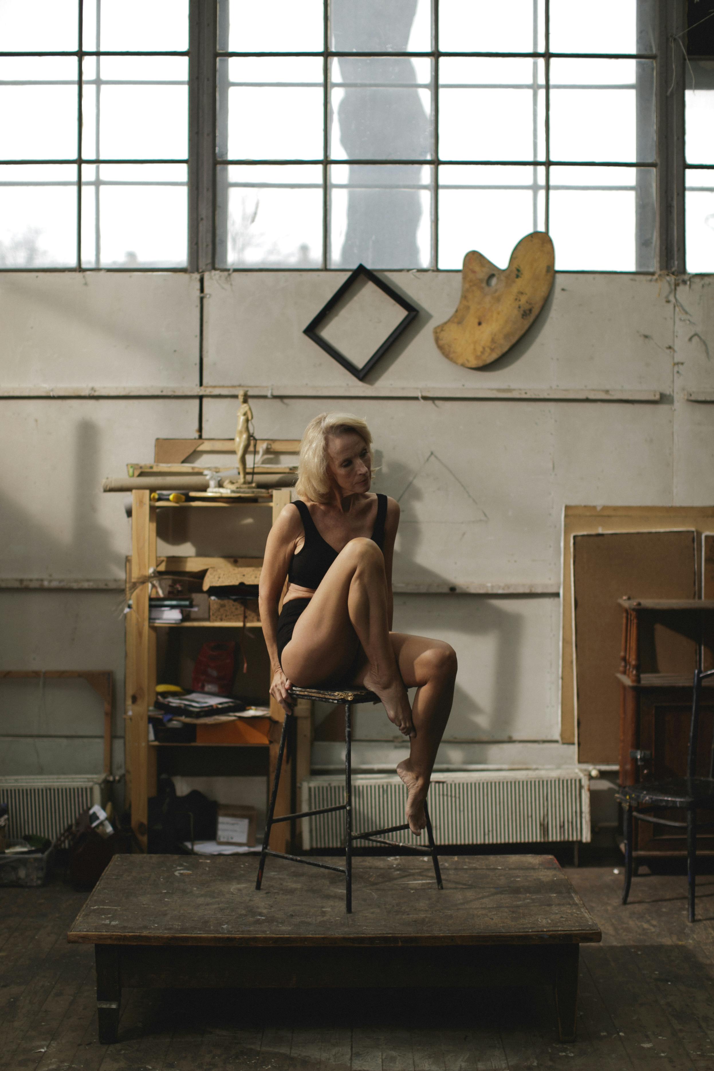 一位资深女性坐在乡村艺术工作室的椅子上，周围环绕着创意元素