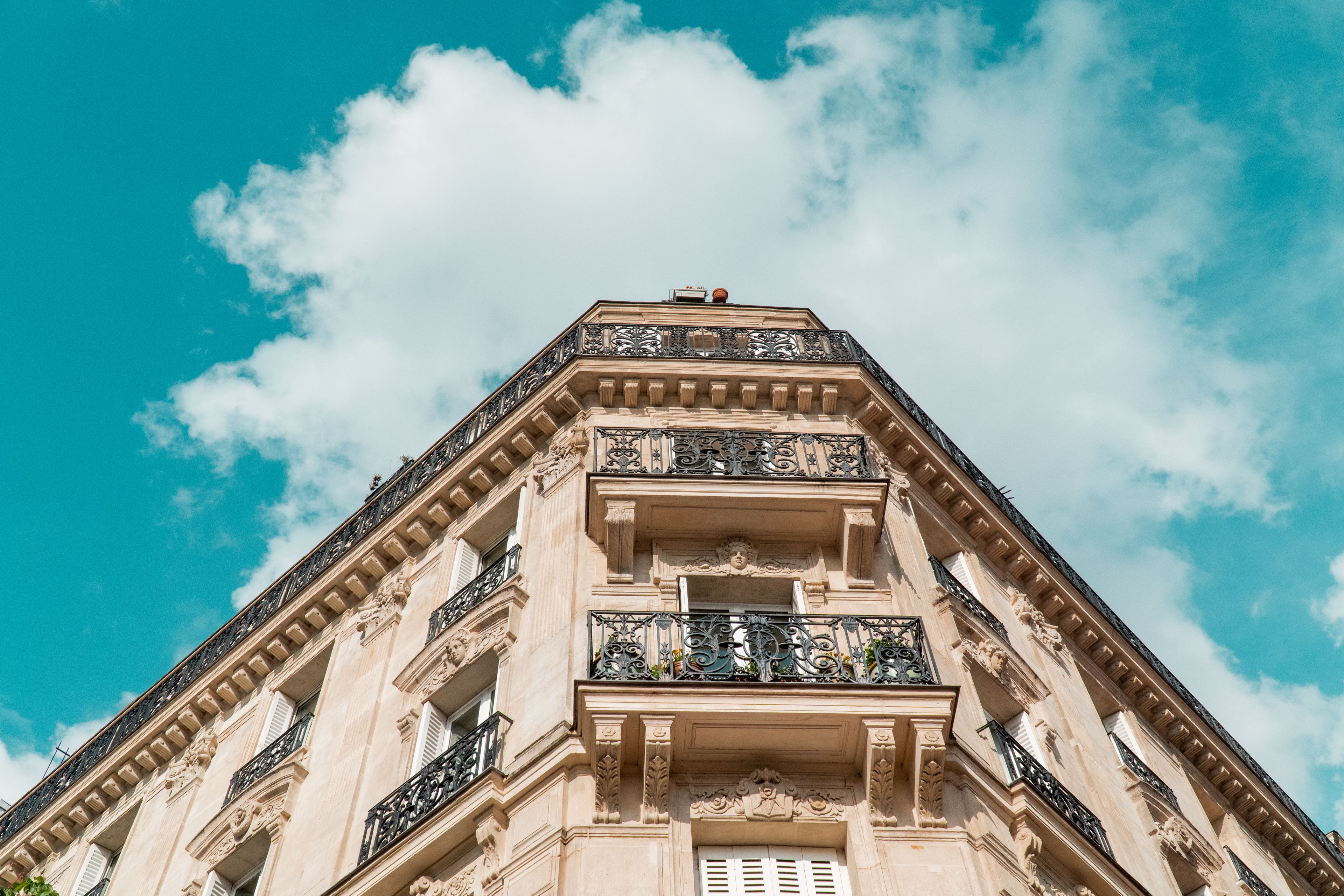 Façade parisienne aux balcons filants ouvragés, se détachant sur un ciel vif.