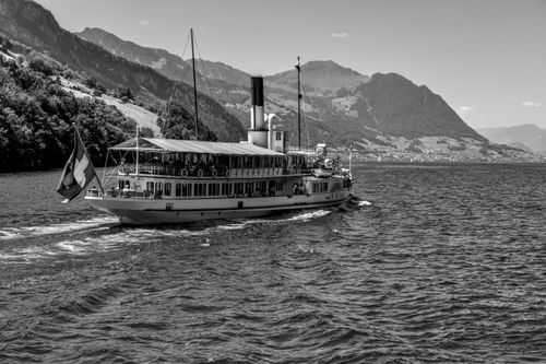 Free Vintage steamboat cruising on Lake Lucerne with scenic mountain backdrop. Black and white photography. Stock Photo
