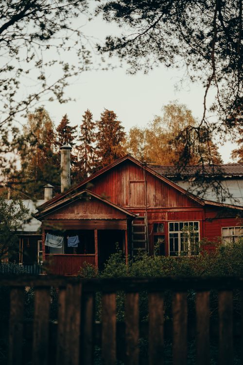 Free Charming red cottage nestled in a serene forest, evoking a warm and cozy ambiance. Stock Photo