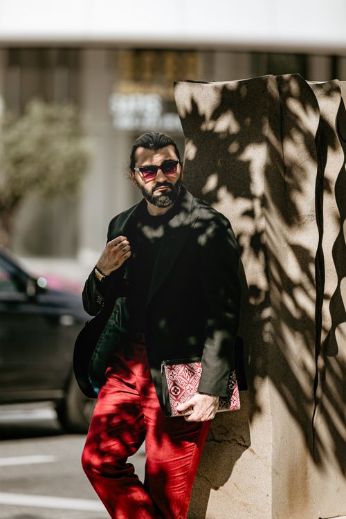 Free Chic man in black coat and red pants, leaning against Baku architecture, embodies urban sophistication. Stock Photo