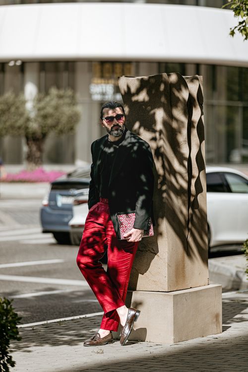 Free Fashionable man in red pants and sunglasses leaning against column in Baku cityscape. Stock Photo