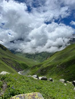 Breathtaking view of a green alpine valley with clouds in Himachal Pradesh, India.