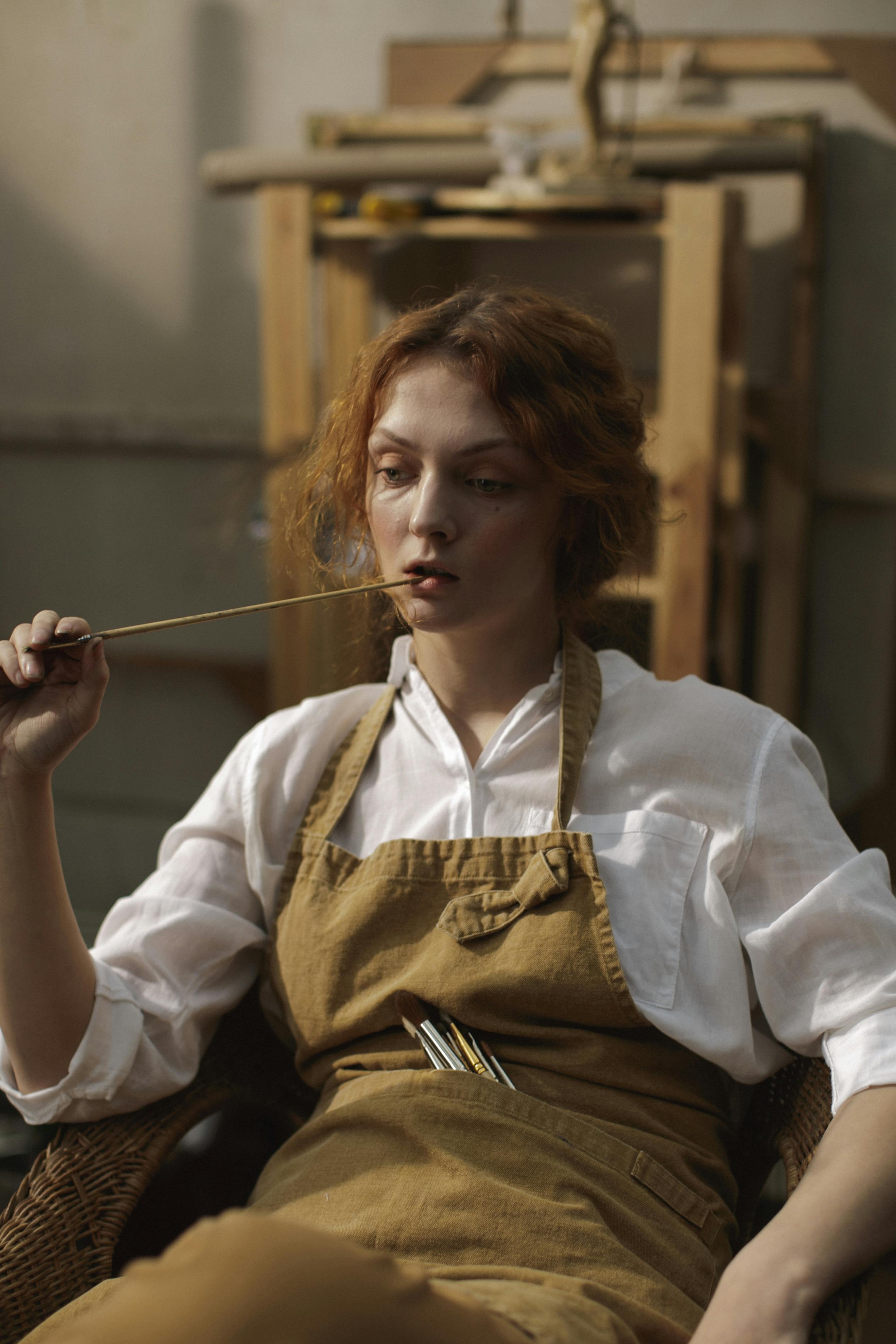 woman in white long sleeve holding wooden paint brush