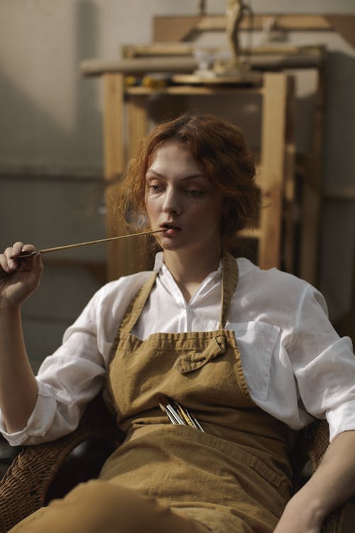 Free Woman in White Long Sleeve Holding Wooden Paint Brush Stock Photo