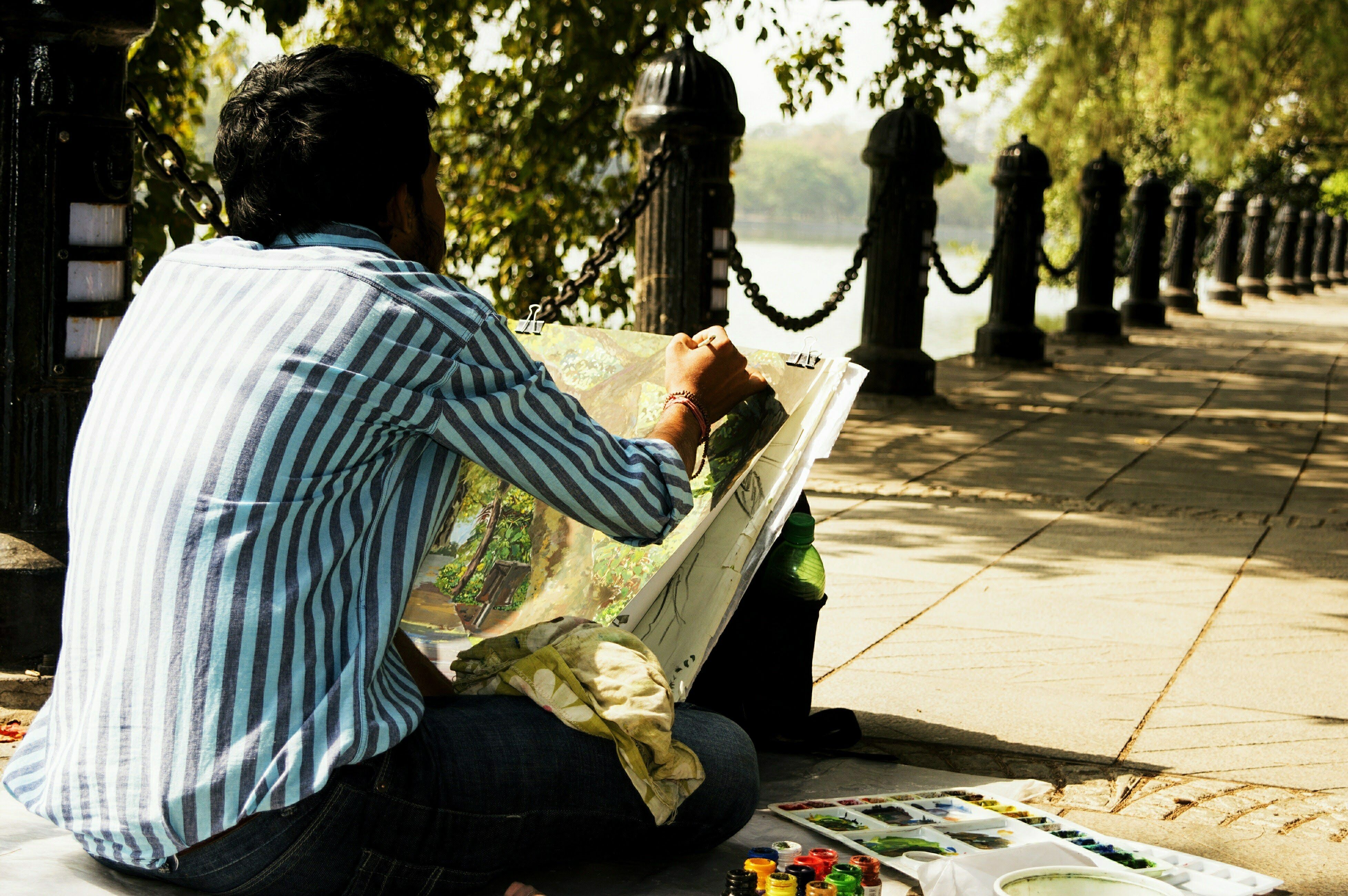 A street artist paints on a canvas beside the scenic riverside in Kolkata, India.