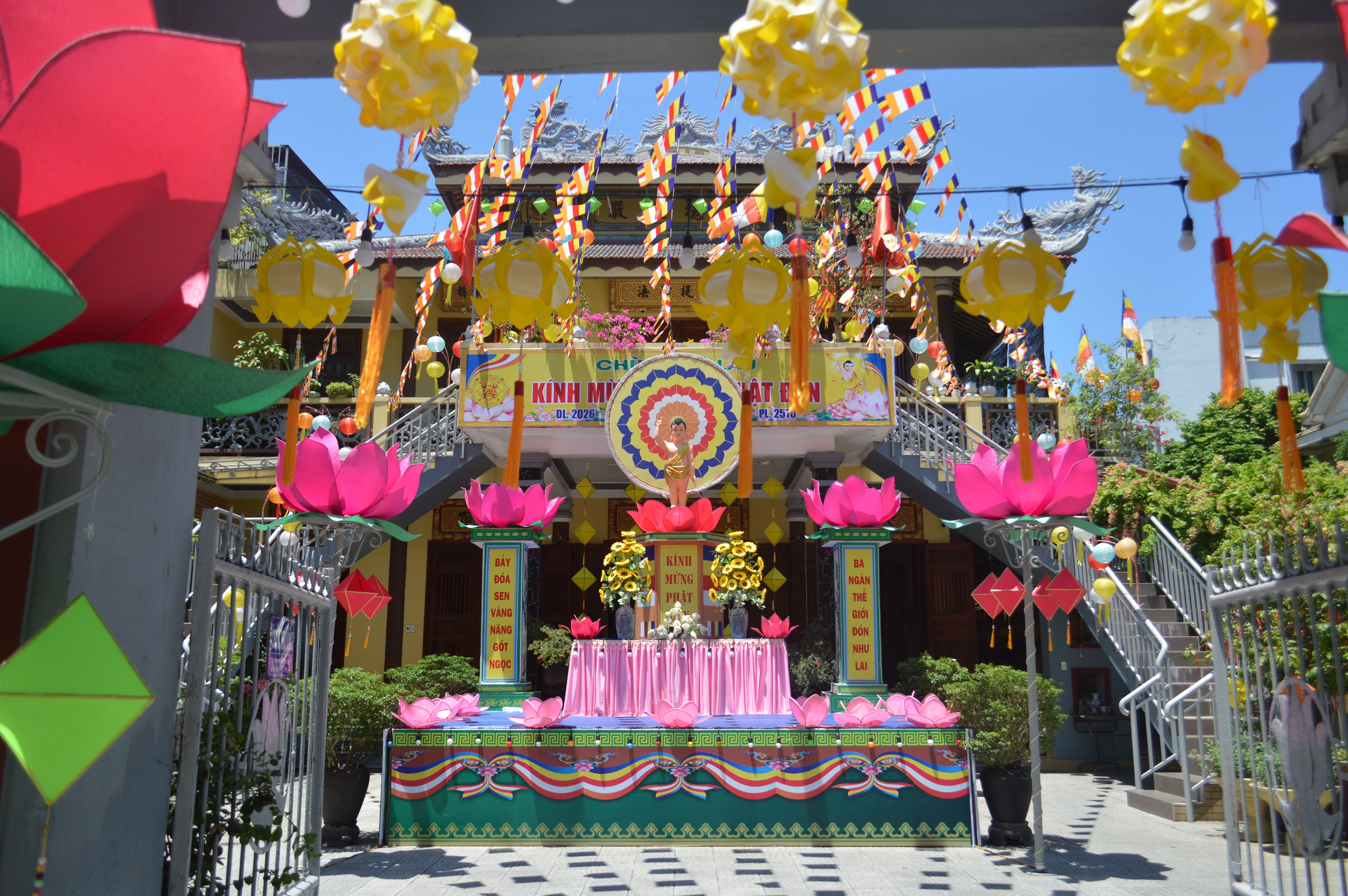 Vibrant decorations at a Buddhist temple celebrating Vesak, featuring colorful lanterns and floral displays.