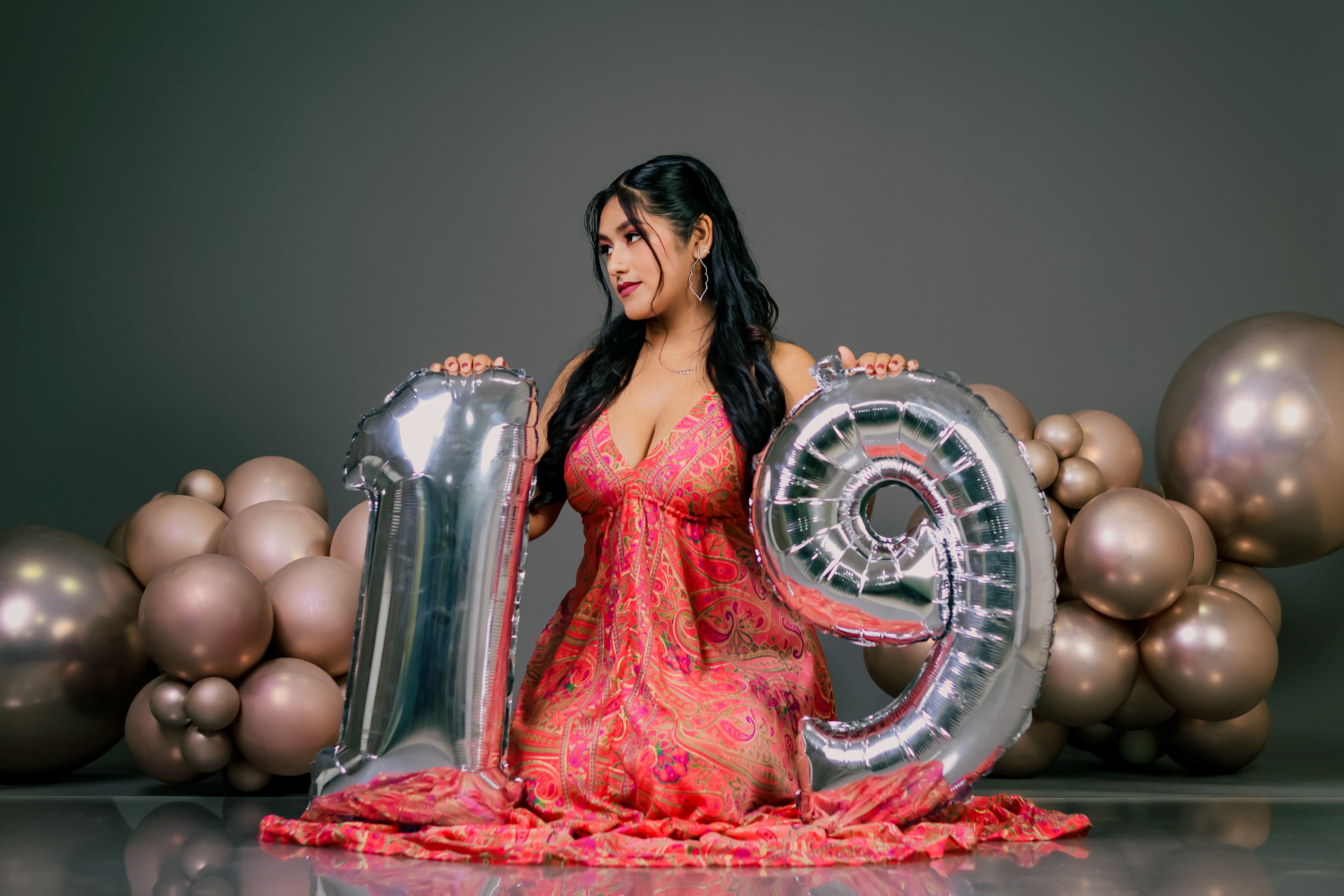 Woman in a pink dress celebrating her 19th birthday with balloons indoors.