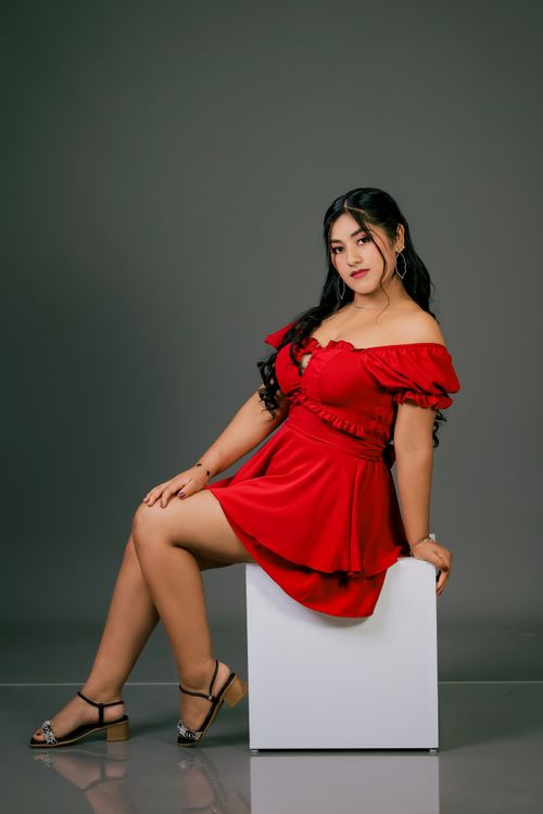 Free Woman posing in red dress against a modern, minimalist backdrop. Stock Photo