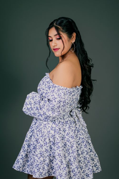 Free Elegant portrait of a woman in a floral dress with a confident pose against a neutral backdrop. Stock Photo