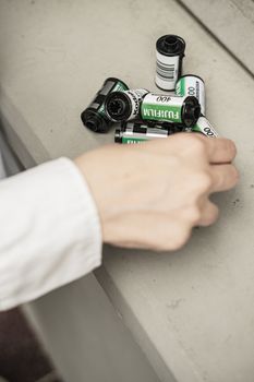 A collection of Fuji 35mm film rolls on a table with a hand reaching in.