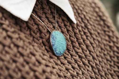 Free A stylish blue pendant necklace resting on a brown knit sweater for fashion elegance. Stock Photo