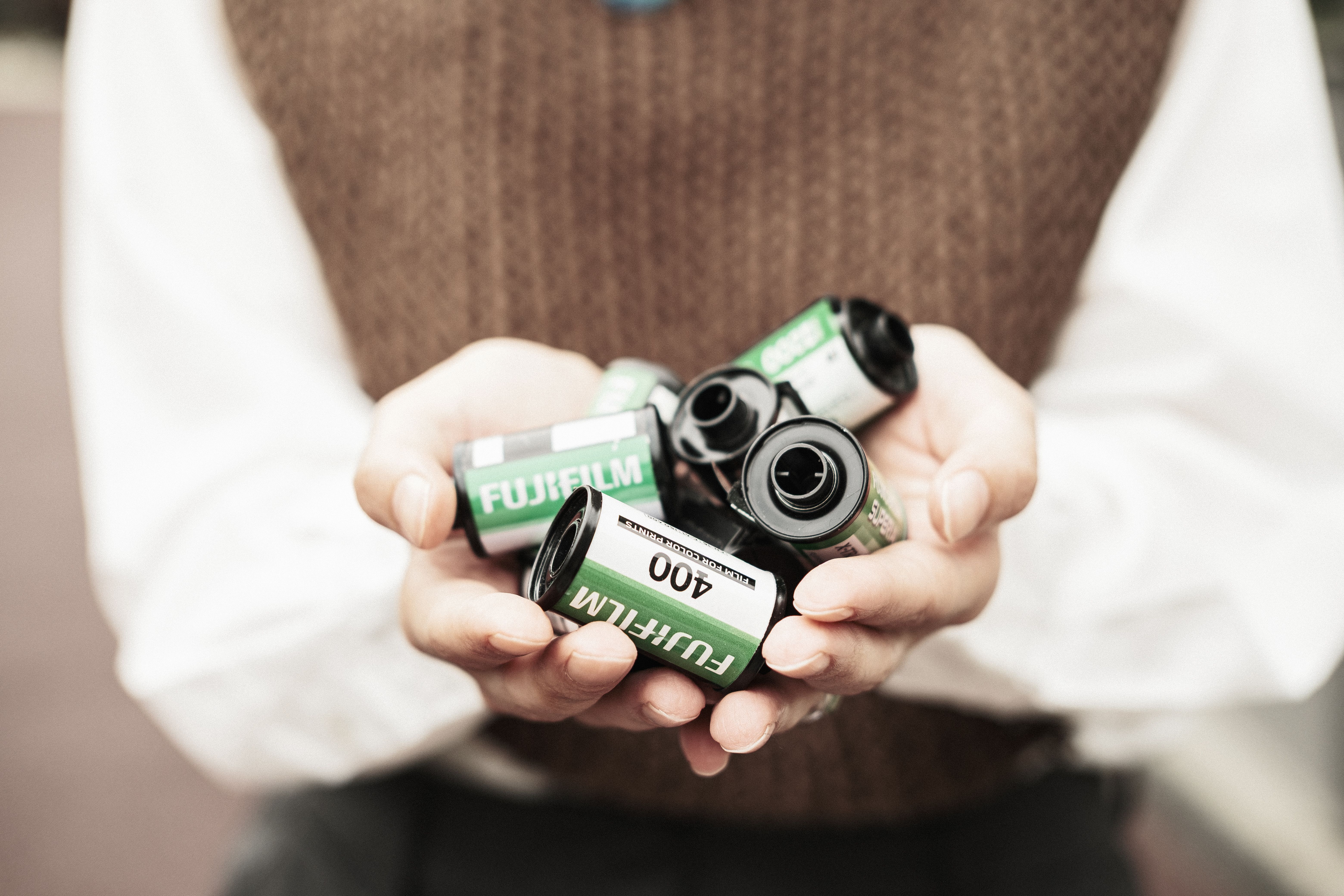 Close-up of hands holding multiple Fujifilm 400 film rolls, symbolizing vintage photography.