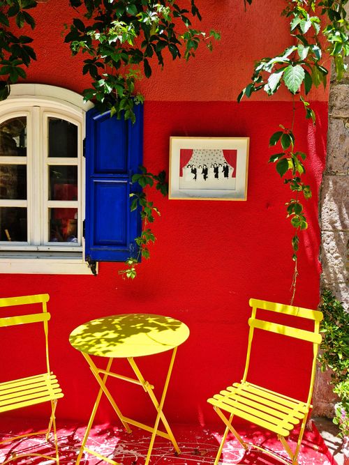 Free Bright red wall with blue window and yellow patio set in Balıkesir, Türkiye. Stock Photo